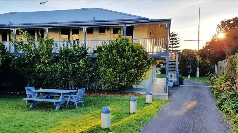 Front view of Point Lonsdale Guesthouse accommodation in Point Lonsdale Bellarine Peninsula with front garden and picnic table, driveway and view of the house and verandah at dusk.