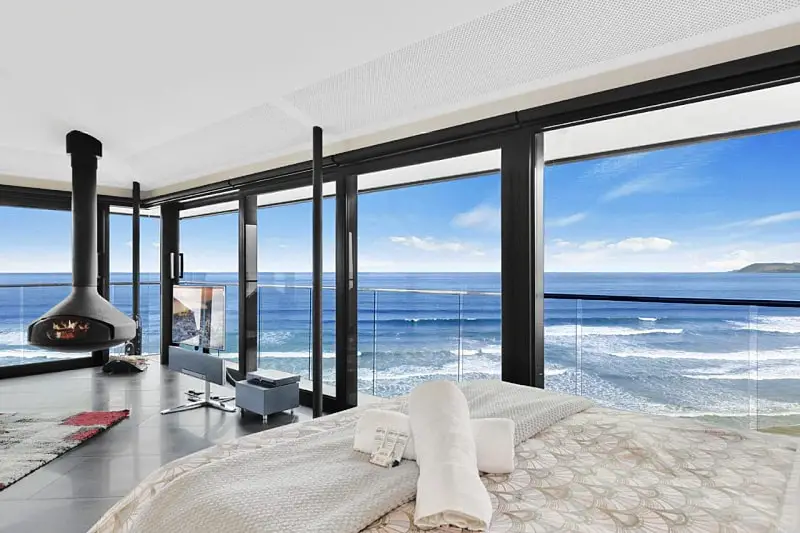 View of the bed and ocean from inside The Pole House accommodation at Aireys Inlet on the Great Ocean Road.