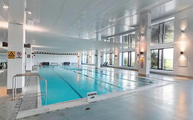 Indoor pool with a wall of windows at The Sands Torquay resort accommodation.