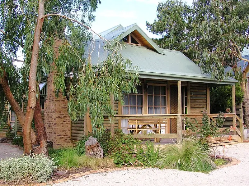 A wood cabin with a verandah surrounded by gum trees at Ti-Tree Village accommodation in Ocean Grove on the Bellarine Peninsula in the state of Victoria.