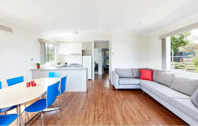 Open plan living area with couch, dining area , and kitchen in a Torquay Foreshore Caravan Park cabin.