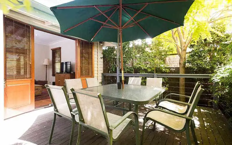Back deck with a picnic table and open green umbrella at Abaleen House one of the recommended places to stay in Queenscliff.