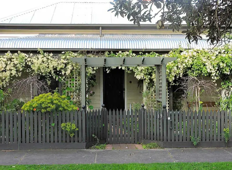 Front entrance to Delightful Cottage it has a green fence, a verandah covered in vines and a black front door. Delightful Cottage is a great place to stay in Queenscliff on the Bellarine Peninsula. 