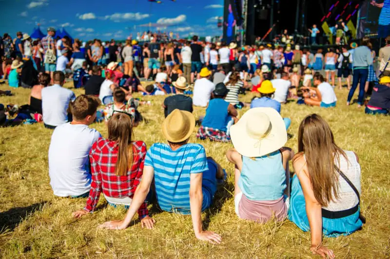 Group of young people wearing sun hats sitting on the grass at a music festival. The Queenscliff Music Festival attracts thousands of people every year.
