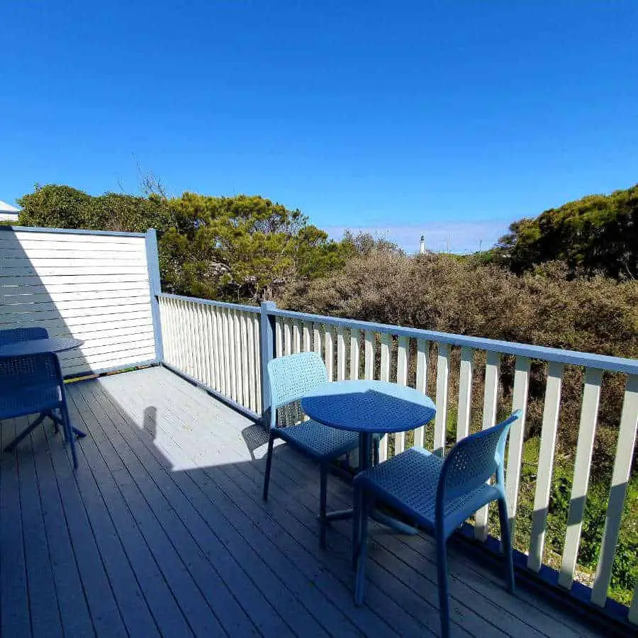 Balcony with a table and chairs with views across the trees to the coast at Point Lonsdale Guest House.