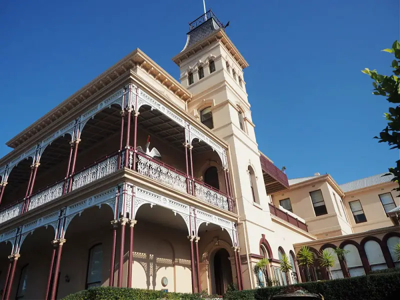 View of a two storey heritage building in Queenscliff. It has a balcony and verandah with decorative fretwork and a tower with a turret. Many of these buildings can be seen on a Queenscliff Heritage Walk tour.