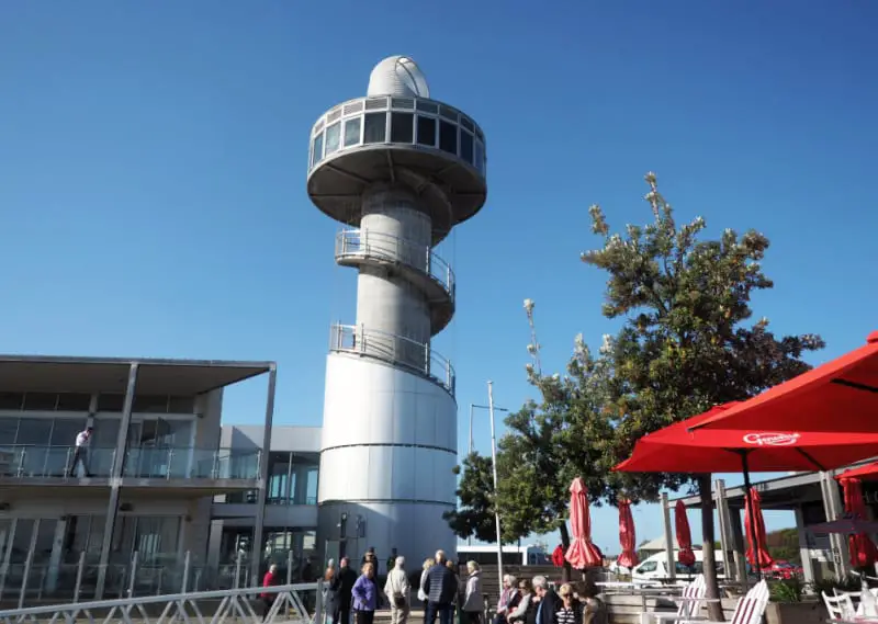 A group of tourists gathered at the base of the Queenscliff Observation Tower. Located at the Queenscliff Harbour it is one of the top Queenscliff attractions.