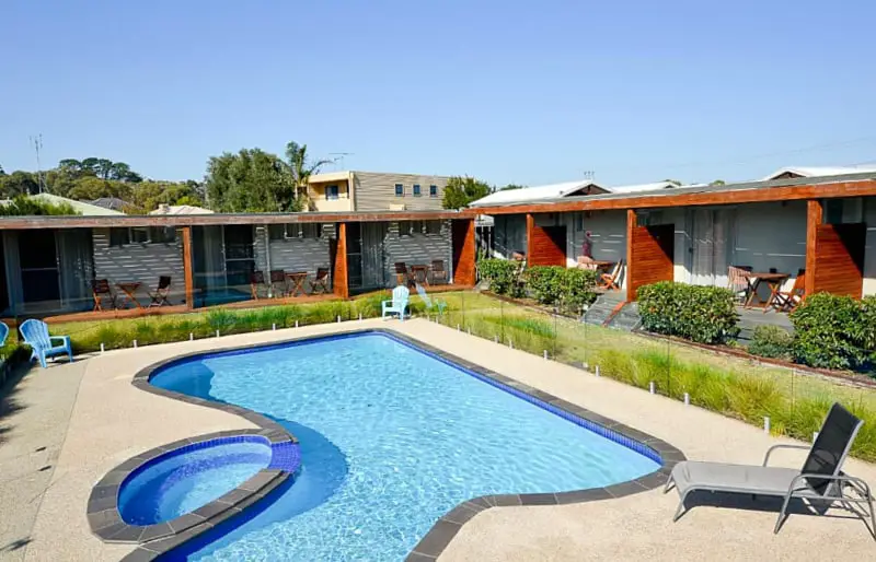 Pool area surrounded with a lounge chair and garden surrounded by motel rooms at Riverside Ocean Grove on The Bellarine. 