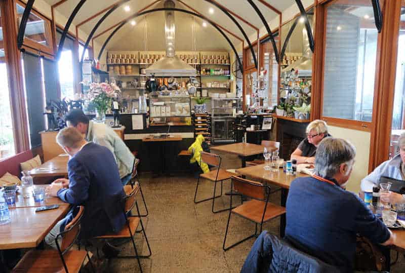 People enjoying a meal at Shelter Shed in Queenscliff. The decorative ceiling has black and brown curved  beams. 