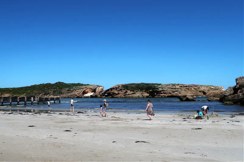 The white sand beach of Staingray Bay with views of Middle and Merri Islands and families enjoying the beach. Stingray Bay is  a good family friendly beach in Warrnambool.