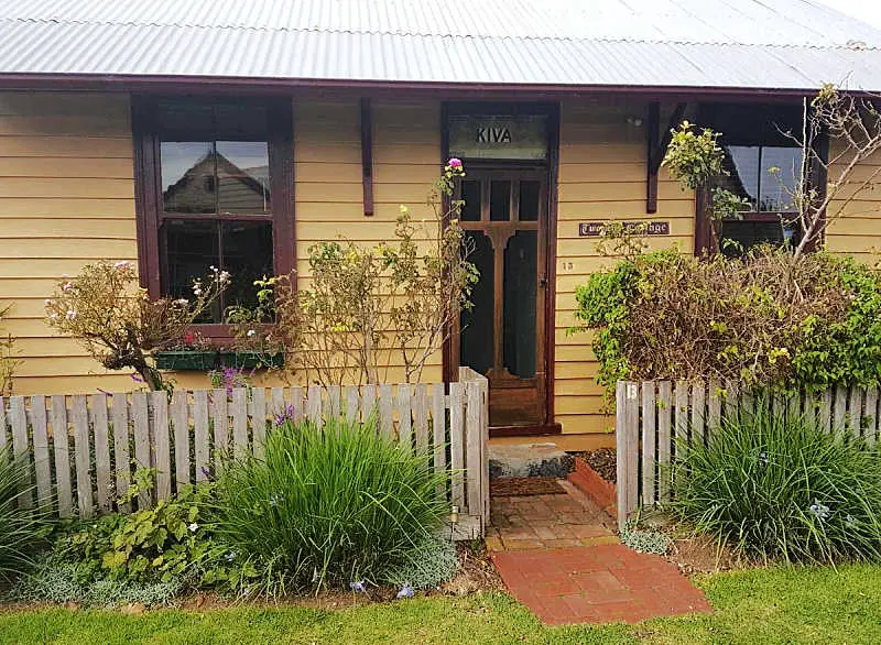 Front entrance to Twomeys Cottage. There is a picket fence with lavender bushes and a short path leading to the front door. Twomeys Cottage is a delightful place to stay in Queenscliff.