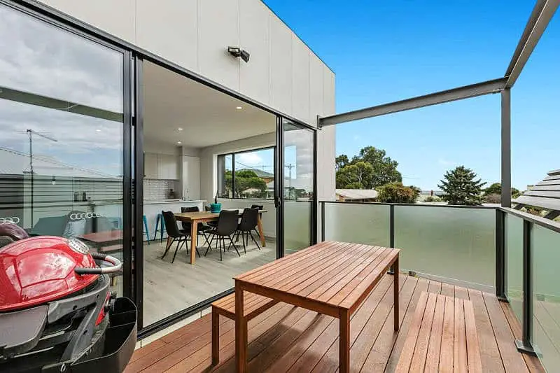Balcony with outdoor furniture and barbecue with views inside through open sliding doors at Waterline Property Portarlington accommodation on the Bellarine.