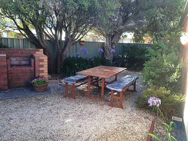Garden area with trees, a picnic table, and barbecue at Beachcomber Motel & Apartments in Apollo Bay Victoria Australia.