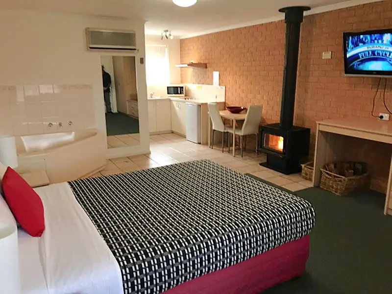 Guest room at Beachcomber Motel & Apartments in Apollo Bay with a bed, wood burner heater, a kitchenette, and spa bath.