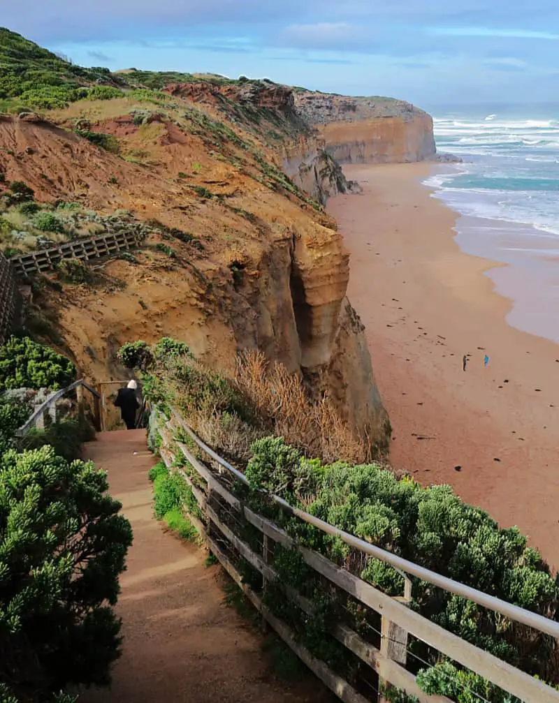 Person walking down Gibson Steps to the beach on the Great Ocean Road where you can view the cliffs and rock stacks. You'll stop here when visiting from Melbourne on a Great Ocean Road tour.
