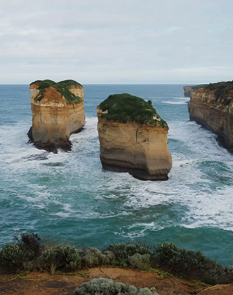 Huge rock stacks topped with greenery in jewel coloured sea on the Great Ocean Road in Victoria Australia.