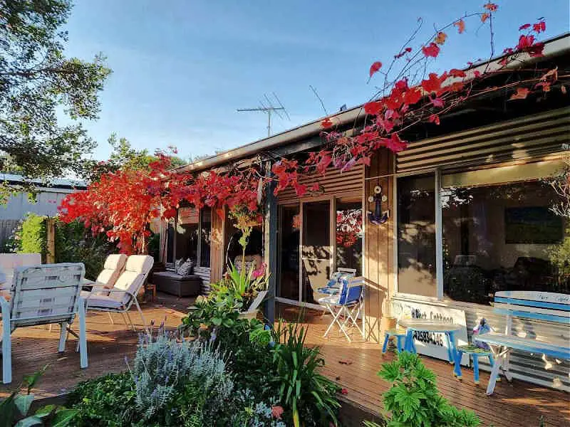 Garden area with outdoor furniture and a red coloured climbing plant at Little Port Cottage in Portarlington.