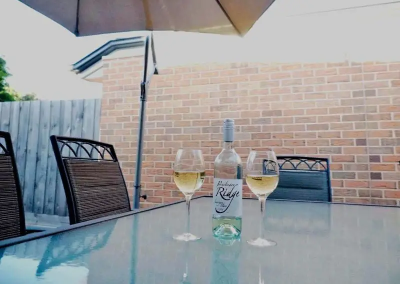 Alfresco dining area at Port Relaxation with a bottle of wine and two glasses sitting on the table. One of the top options for places to stay in Portarlington Victoria.