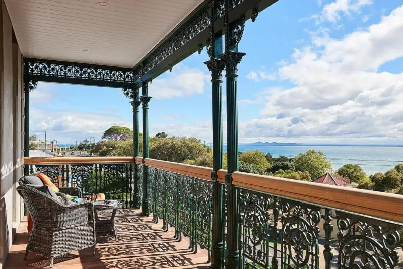 Balcony with views across the bay to the You Yangs at Portarlington Grand Hotel. There are comfortable chairs and a small table for relaxing with a drink.