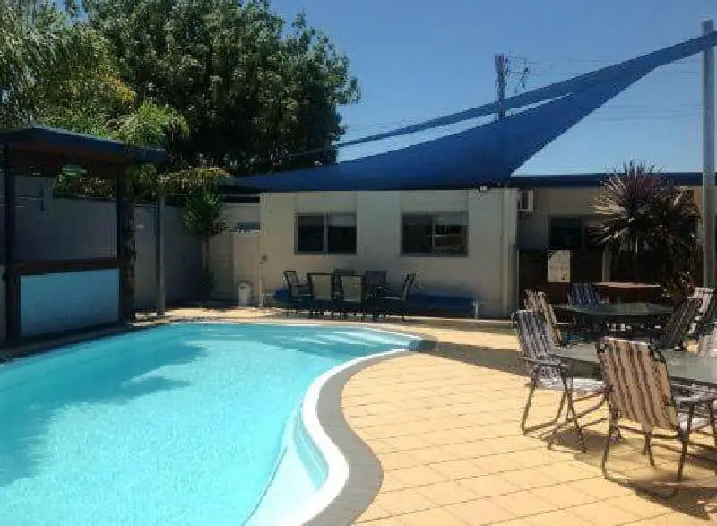 Tiled pool area with sun lounges and outdoor table and chairs at Portarlington Beach Motel affordable Portarlington accommodation.