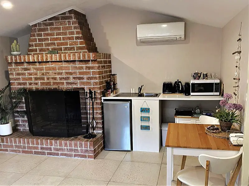 Kitchen area with an open fire place and a small table for two at The Cosy Bungalow a great place to stay in Portarlington for couples.