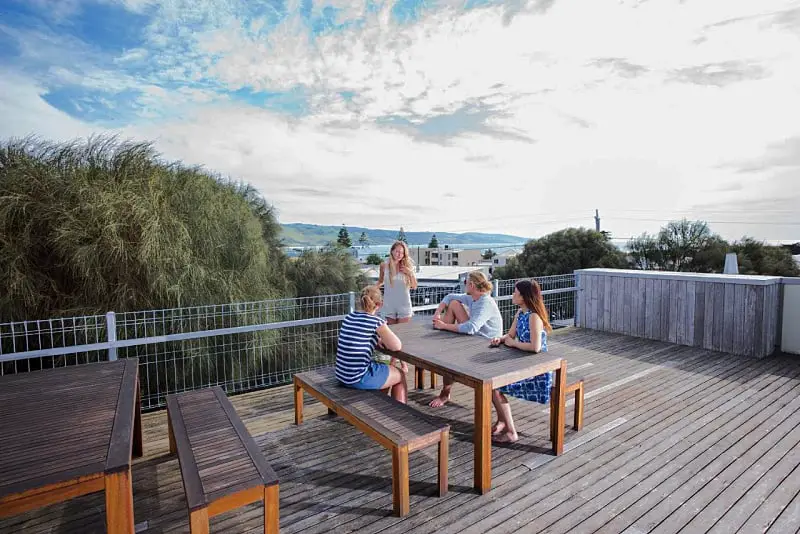 People sitting at a balcony table enjoying the views at YHA Apollo Bay Eco accommodation. 