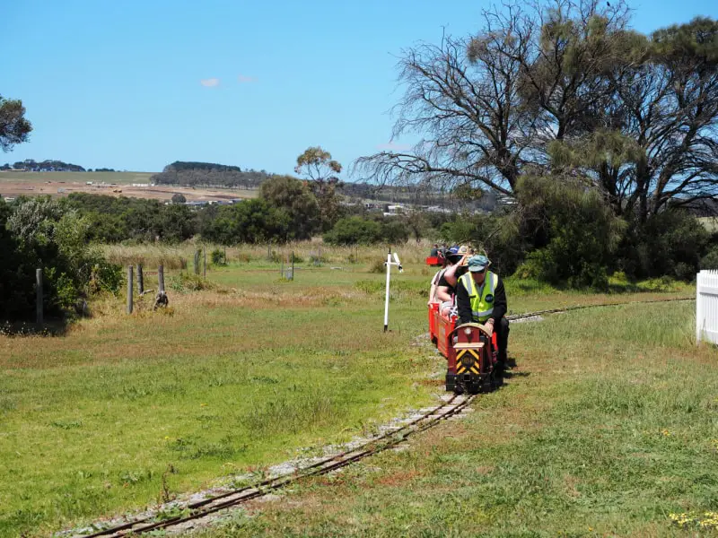 Miniature train riding along the tracks on a clear day surrounded by countryside in Portarlington. Riding the miniature train is one of the fun things to do in Portarlington for kids.