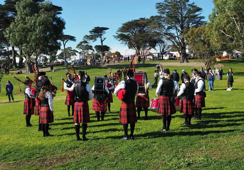 A marching band performing in a circle wearing red kilts at the National Celtic Festival in Portarlington Australia. 