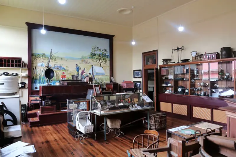 Room filled with historical artefacts at the Daylesford & District Musem there is a large framed painting of a goldfields campsite on the wall.