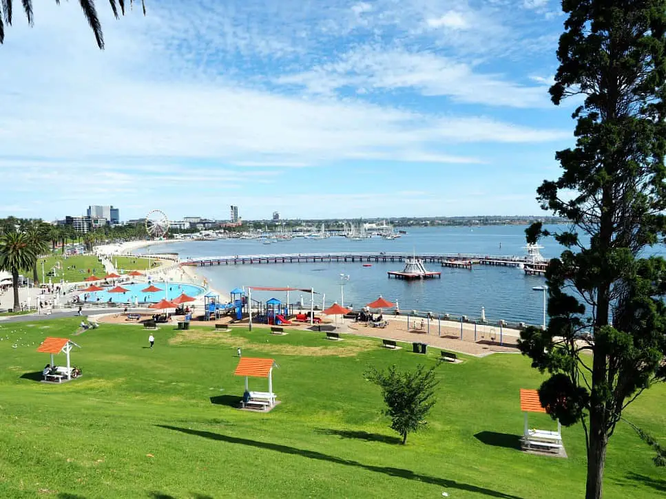View of Eastern Beach the most popular Water Geelong attraction. The promenade, childrens' pool, beach, and Giant Sky Wheel can be seen and the sloping lawns and picnic tables are in the foreground.