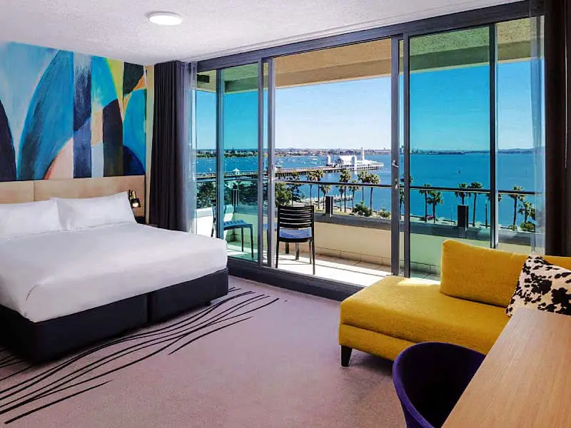 Guest room at Novotel Geelong Hotel with glass sliding doors that open to a balcony with views over Corio Bay. A beautiful Geelong Waterfront Hotel.