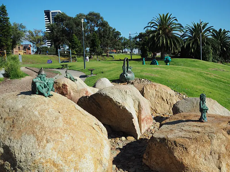 Image of small sculptures sitting on rocks at the Poppy Kettle Playground in Geelong. The sculptures are of miniature people from Peru and a kettle taken from a fairy tale.