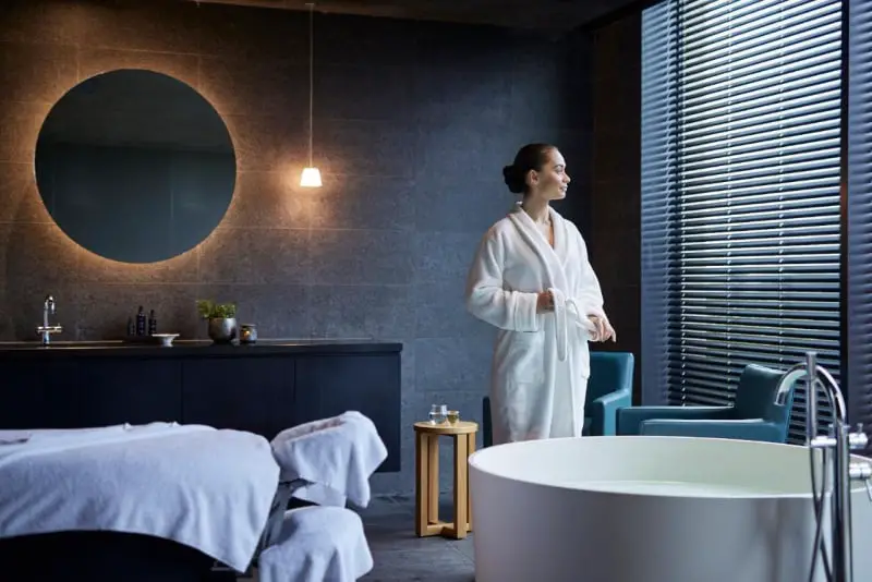 Woman wearing a bathrobe standing beside a round bath at RACV Resort Torquay.