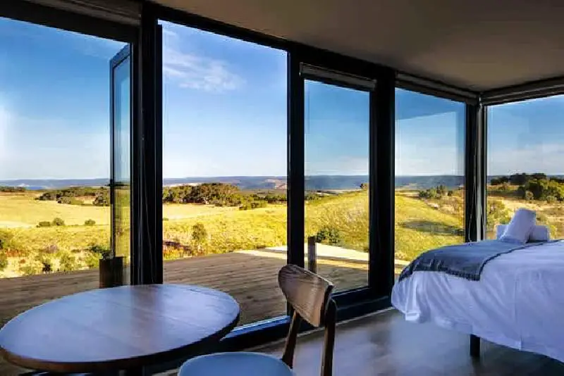 A round table and chair sitting next to the open glass doorway with coastal views at Sky Ship 1 luxury holiday accommodation in Cape Otway Great Ocean Road Victoria. 