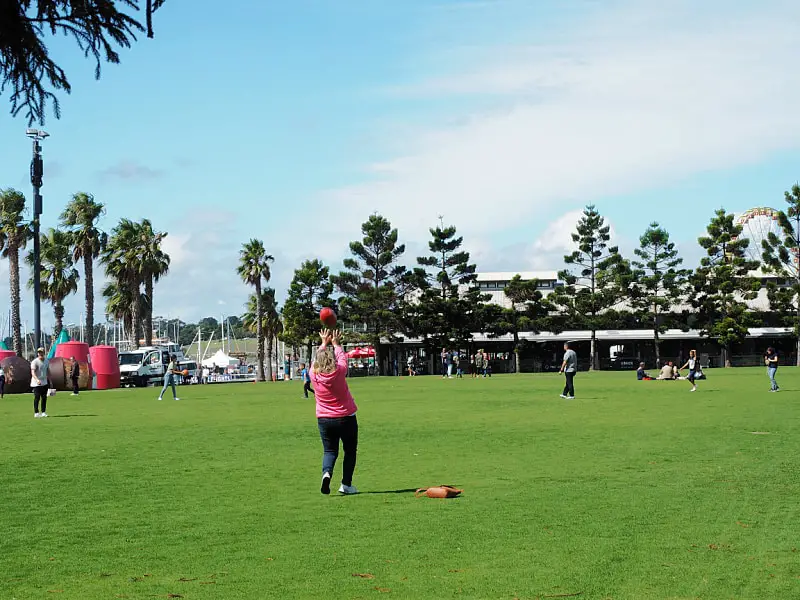 Woman catching a football at Steampacket Gardens Geelong Waterfront.