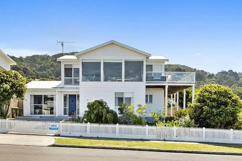 View of the Art House in Apollo Bay. The two storey house is painted white and has a white picket fence around it.