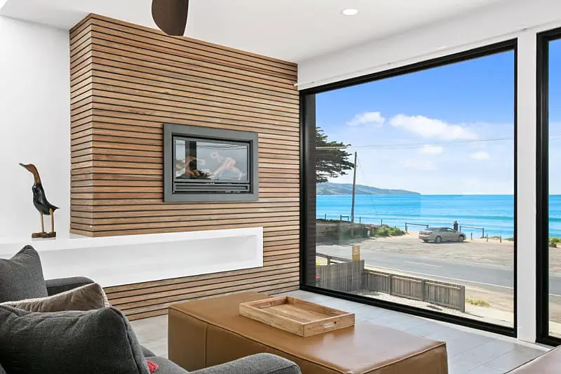 Sitting area with couch and coffee table and floor to ceiling windows with ocean views at Apollo Bay Beach House one of the best holiday rentals in Apollo Bay.